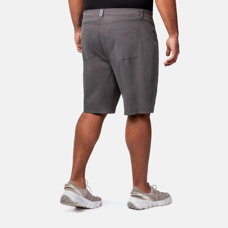 A man, seen from behind on a white background, wears a black shirt, Clearance Men's Stretch Active Poplin Trek Cargo Shorts in gray with back pockets, and light gray athletic shoes.