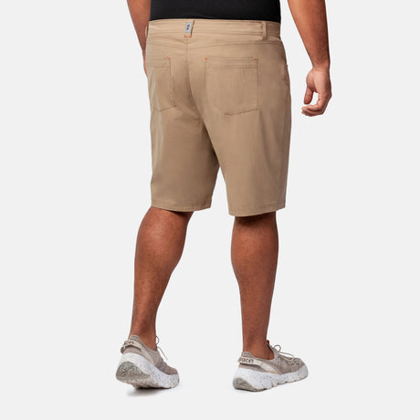 A person wearing tan Clearance Men's Stretch Active Poplin Trek Cargo Shorts, a black shirt, and light sneakers faces away, showcasing the shorts' back pockets and seams against a plain white background.