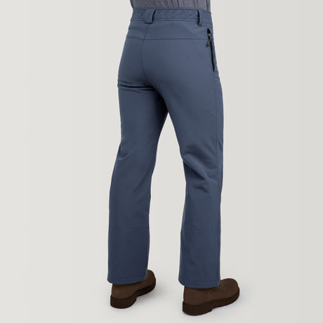 A person is seen from the back wearing Clearance Men's Ascend Flex Softshell Ski Pant in blue with a right zip pocket and belt loops, paired with brown shoes, against a plain light background.