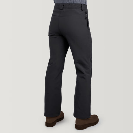 A person is shown from the back wearing Clearance Men's Ascend Flex Softshell Ski Pant in dark gray with belt loops and a right-side zippered pocket, paired with brown shoes against a plain light background.