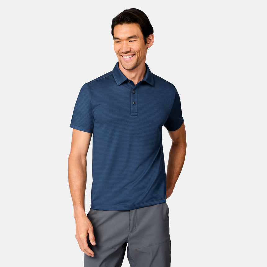 [Scott is 6’3" wearing size M] Man wearing a dark blue polo shirt and gray pants on a white background