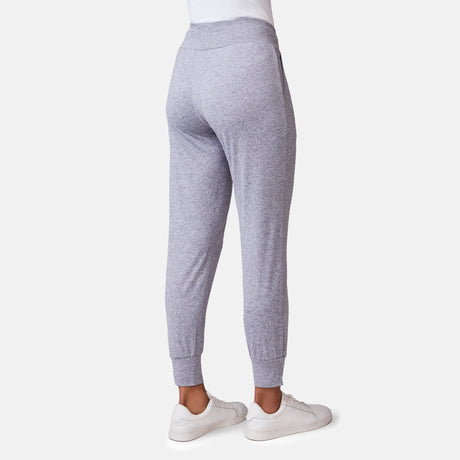 A woman wears Free Country’s Women's Cloud Knit Pleated Jogger in light gray with white sneakers, shown from the back against a plain white background.