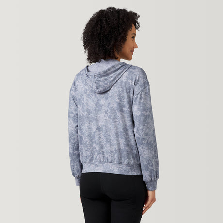 A woman with curly hair faces away, wearing the Clearance Women's Cloud Knit Zip Hoodie in blue-gray with black pants, set against a plain light background.