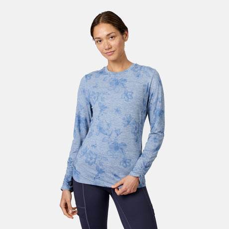 A woman wears the Free Country Women’s Cloud Knit Crew Neck Top in Dusk Blooms with dark leggings, standing against a plain light background, smiling slightly at the camera with one hand on her hip.