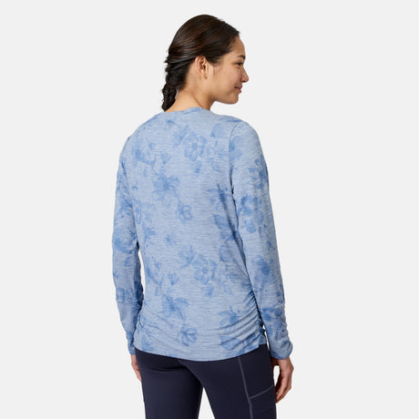 A woman with a braid is seen from behind in a Free Country Women’s Cloud Knit Crew Neck Top, light blue floral, and dark leggings against a white background.