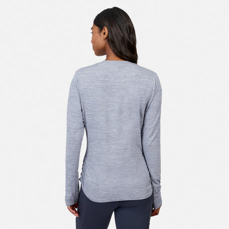 A woman with long dark hair, seen from behind, wears the Free Country Women’s Cloud Knit Crew Neck Top in light gray and dark pants against a plain white background.