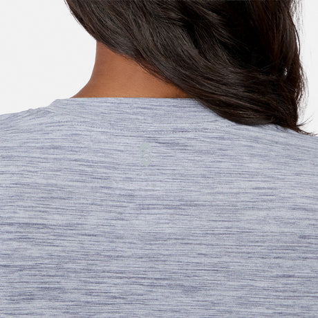 The image features the back of a woman in a heathered light gray Free Country Women’s Cloud Knit Crew Neck Top, with dark hair draped over one shoulder, showcasing the top’s soft cloud knit fabric.