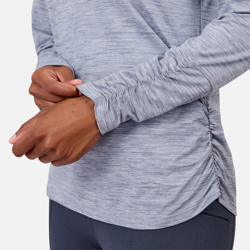 A person adjusts the ruched sleeve of the Women’s Cloud Knit Crew Neck Top by Free Country, shown in light gray with moisture-wicking fabric against a plain white background.