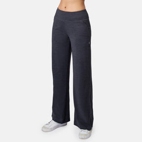 A person wears black Women’s Cloud Knit Wide Leg Pants by Free Country with white sneakers, standing against a plain white background. Only the lower torso and legs are shown.