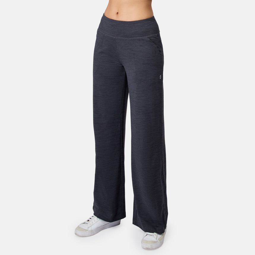 A person wears black Women’s Cloud Knit Wide Leg Pants by Free Country with white sneakers, standing against a plain white background. Only the lower torso and legs are shown.