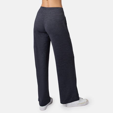 Model seen from the back in dark gray Free Country Women’s Cloud Knit Wide Leg Pants with a high waist and relaxed, wide-leg fit, paired with white sneakers against a plain white background.