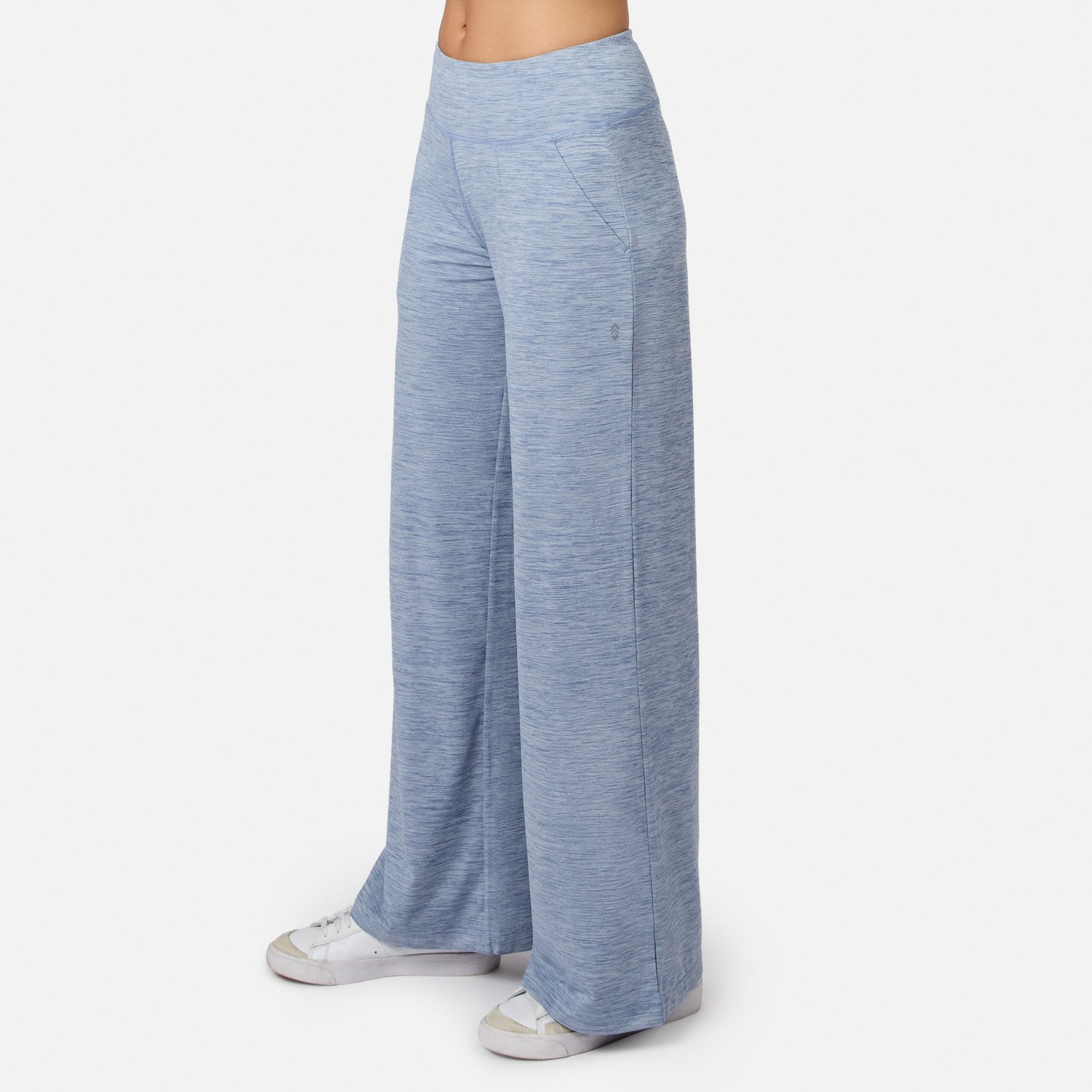 Model wears Free Country Women’s Cloud Knit Wide Leg Pants in light blue with white sneakers, shown waist down against a plain background. These relaxed-fit, moisture-wicking pants feature a subtle heathered texture.