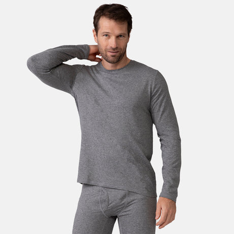 A man models the Men's Cloud Knit Base Layer Top by Clearance—a fitted, long-sleeve gray shirt—against a plain background, with one hand behind his neck, highlighting its moisture-wicking comfort and modern style.