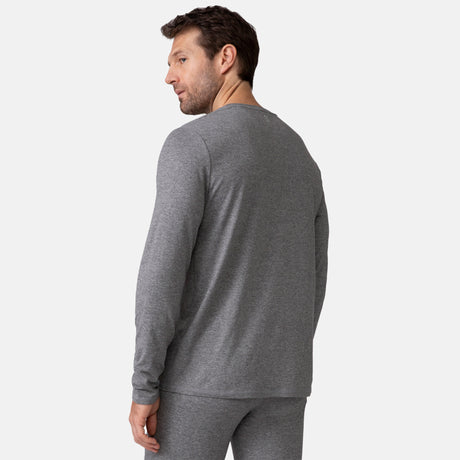 A man wears the Clearance Men's Cloud Knit Base Layer Top and matching gray pants, facing away and glancing over his shoulder. The light background highlights the sleek, moisture-wicking features of his outfit.