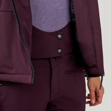 A person wears the Clearance Women's Thermo Super Softshell® Ski Jacket in burgundy with a zipper and black snap buttons at the waist, layered over a light purple top and paired with burgundy pants.