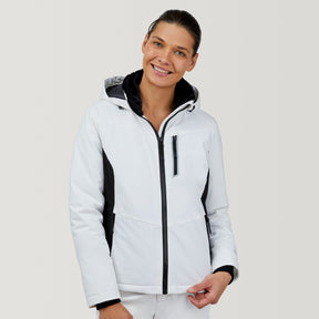 A smiling person wearing the Clearance Women's Thermo Super Softshell® Ski Jacket in white with black accents and hood, stands against a plain light background.