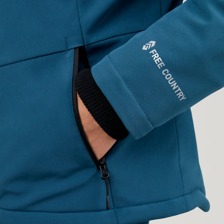 A person wearing a blue Clearance Women's Thermo Super Softshell® Ski Jacket with their hand in a zippered side pocket. The jacket sleeve displays the Clearance logo in white text.