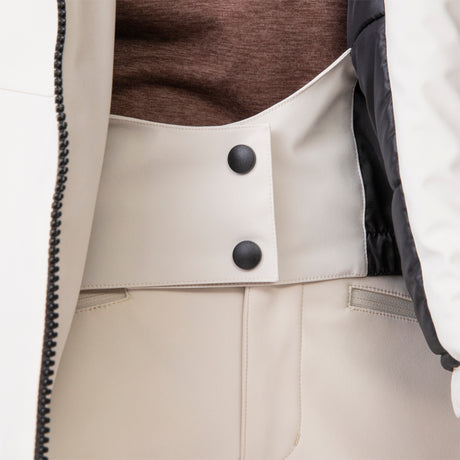 Close-up of a person wearing the Clearance Women's Thermo Super Softshell® Ski Jacket in cream with a black inner lining, styled over a brown top and cream high-waisted pants. The water-resistant material offers both style and function.