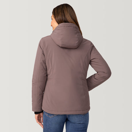 [Olga is 5’9" wearing a size Small.] Woman wearing Free Country Women's FreeCycle® Thermo Super Softshell® II Jacket in light brown with a full front zipper opening, lower pockets, soft lining, a detachable hood with an adjustable drawcord, and water resistant and wind resistant stretch performance fabric, light grey background. Best women’s jacket for winter weather.