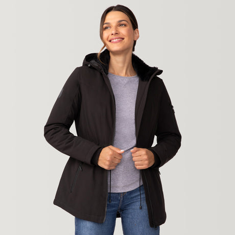 [Olga is 5’9" wearing a size Small.] Woman wearing Free Country Women's Thermo Super Softshell® Long Jacket in black with a full front zipper opening, lower pockets, diamond quilted lining, a hood with an adjustable drawcord, and water resistant and wind resistant stretch performance fabric, light grey background. Best women’s jacket for winter weather.