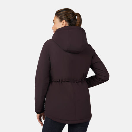 A woman with a brown ponytail wears the Free Country Women's Thermo Super Softshell® Long Jacket with a quilted lining and dark jeans, standing with her back to the camera against a plain white background.