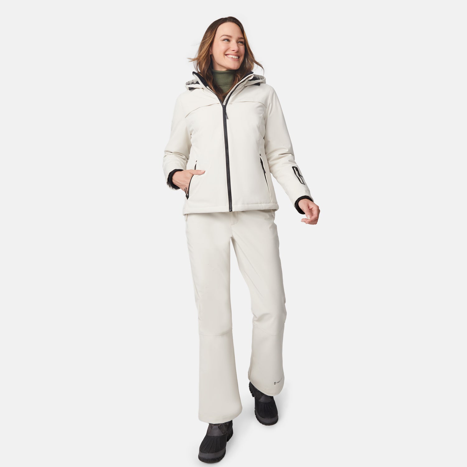 [Model is wearing size S.] Full-body shot of a woman in cream Thermo Super Softshell Lined Jacket and matching pants with zipper details