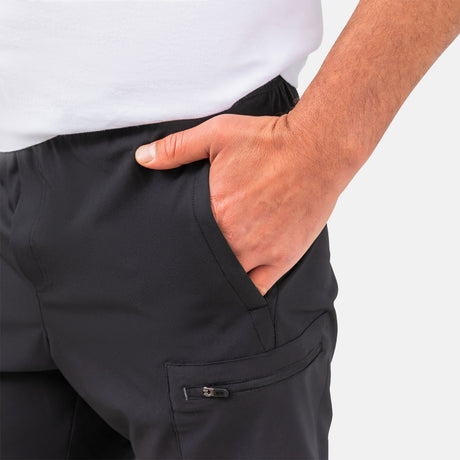 [Model is wearing a size Medium.] Man wearing Free Country Men's Tech Stretch Short II in Black, size M, made from moisture wicking stretch performance fabric featuring an elastic waistband with a drawcord and a side slant pockets, styled with a white t shirt #color_black