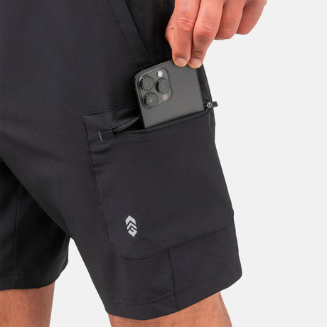 [Model is wearing a size Medium.] Man wearing Free Country Men's Tech Stretch Short II in Black, size M, made from moisture wicking stretch performance fabric featuring an elastic waistband with a drawcord and a side slant pockets, styled with a white t shirt #color_black