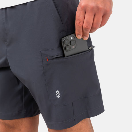 [Model is wearing a size Medium.] Man wearing Free Country Men's Tech Stretch Short II in Charcoal, size M, made from moisture wicking stretch performance fabric featuring an elastic waistband with a drawcord and a side zipper pocket, styled with a white t shirt #color_charcoal