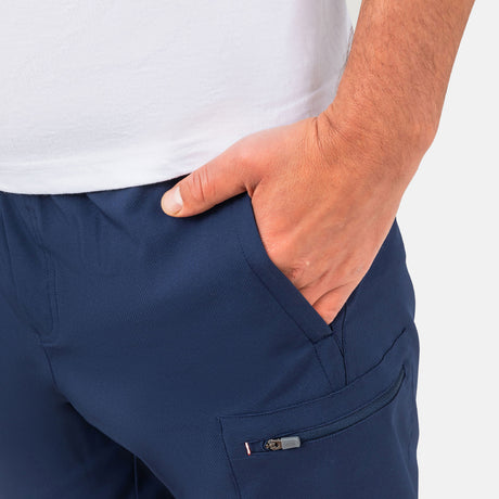 [Model is wearing a size Medium.] Man wearing Free Country Men's Tech Stretch Short II in Slate, size M, made from moisture wicking stretch performance fabric featuring an elastic waistband with a drawcord and a side slant pockets, styled with a white t shirt #color_slate
