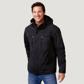 A man smiles while wearing a black Men’s Wild Land Mid Weight Jacket with zippered chest pockets and blue jeans.