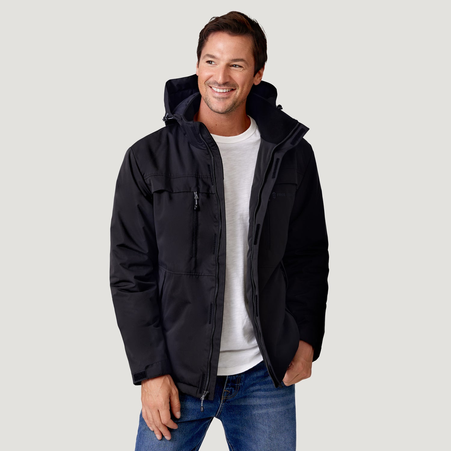 Smiling man wearing a Clearance Men’s Wild Land Mid Weight Jacket over a white t-shirt and blue jeans.