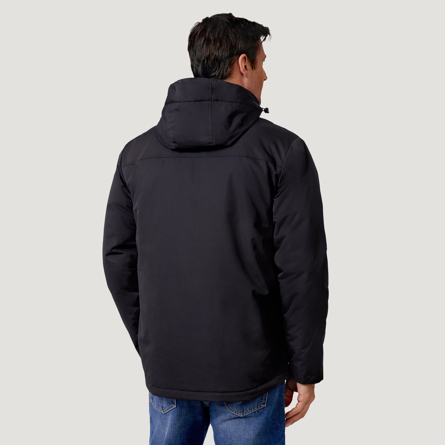 Back view of a person wearing a black Men’s Wild Land Mid Weight Jacket and blue jeans.