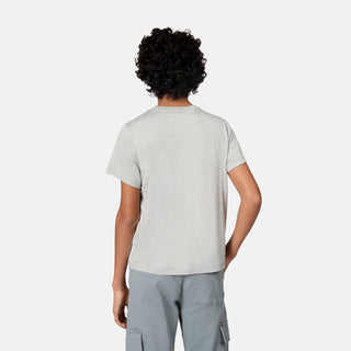 A person with short curly hair is standing with their back to the camera, wearing the Free Country Boys' Microtech® Graphic Crew Neck Shirt in light gray and gray cargo pants against a plain white background.