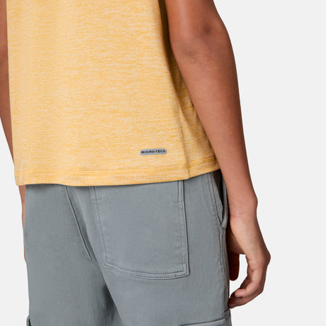 A person wears a yellow heathered Free Country Boys' Microtech® Crew Neck Shirt with grey shorts, ideal for everyday comfort.