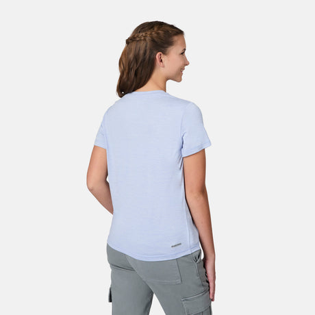 A girl with brown braided hair stands facing away, wearing a light blue Free Country Girls' Microtech® Crew Neck Shirt and gray cargo pants against a plain white background.