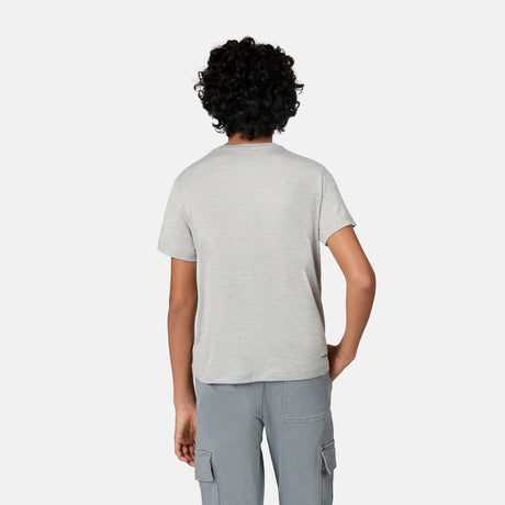 A boy with curly hair stands with his back to the camera, wearing a light gray Free Country Boys' Microtech® Crew Neck Shirt and gray cargo pants against a plain white background.