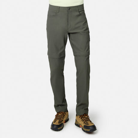 Lower body visible: person wears Free Country Men’s Nylon Stretch Convertible Pant in olive green—four-way stretch, water-repellent, converts to shorts via below-knee zippers—paired with brown hiking boots. Plain white background.