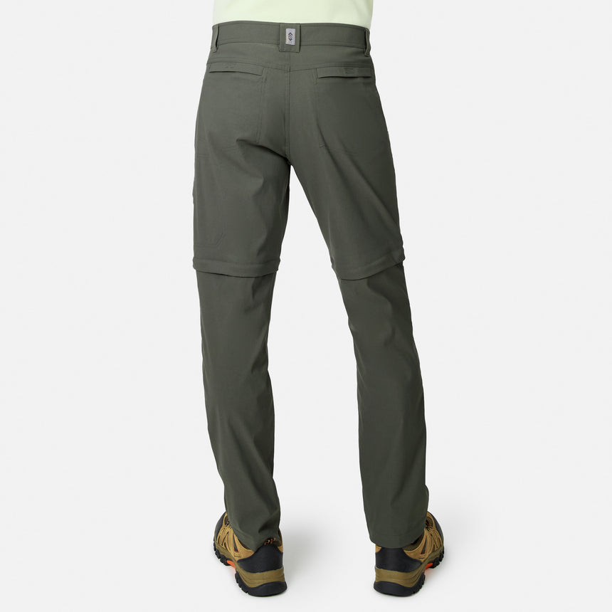 Model wears Free Country Men’s Nylon Stretch Convertible Pant in olive green, featuring water-repellent fabric, two back pockets, and zippered knees; shown from the back with brown hiking shoes on a white background. Easily converts to shorts.