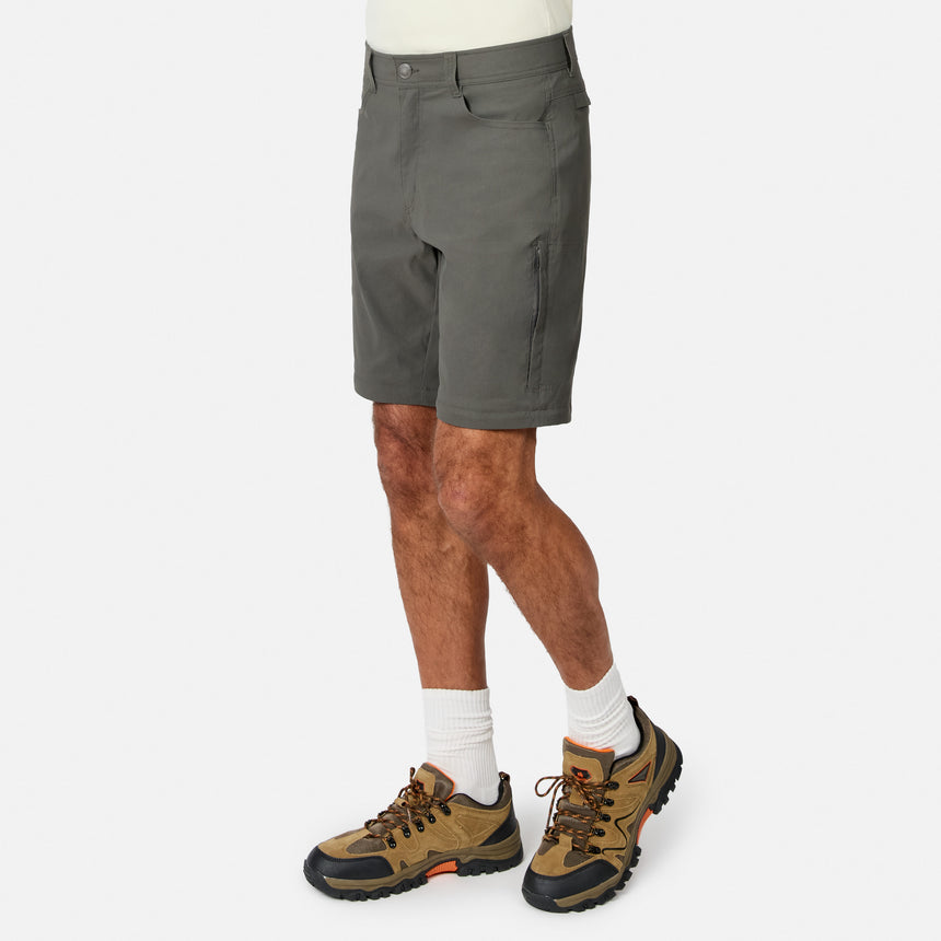 A person models the lower half, wearing Free Country Men’s Nylon Stretch Convertible Pant. Only gray pants, white socks, and brown hiking shoes are visible against a plain white background.
