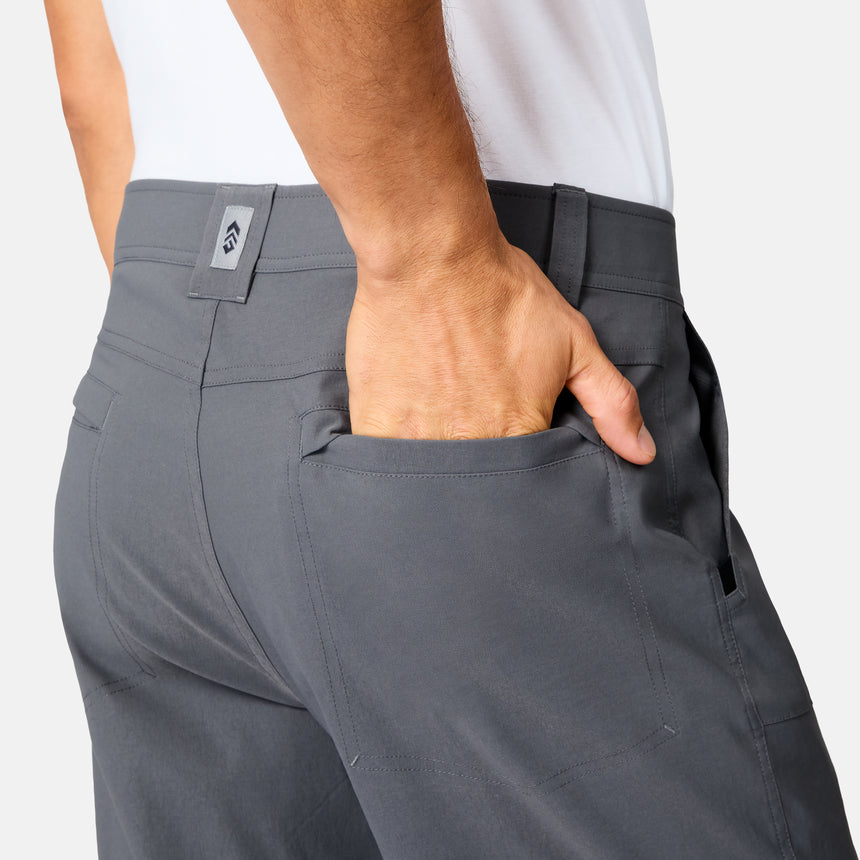 A person wearing Free Country Men’s Nylon Stretch Casual Trek Pant in gray and a white shirt is shown from the back, with their right hand partially inside the back pocket.