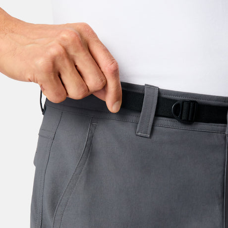 A person adjusts the black waistband of Free Country Men’s Nylon Stretch Casual Trek Pant in gray, featuring a built-in belt. They’re paired with a white shirt for a sleek, versatile look.