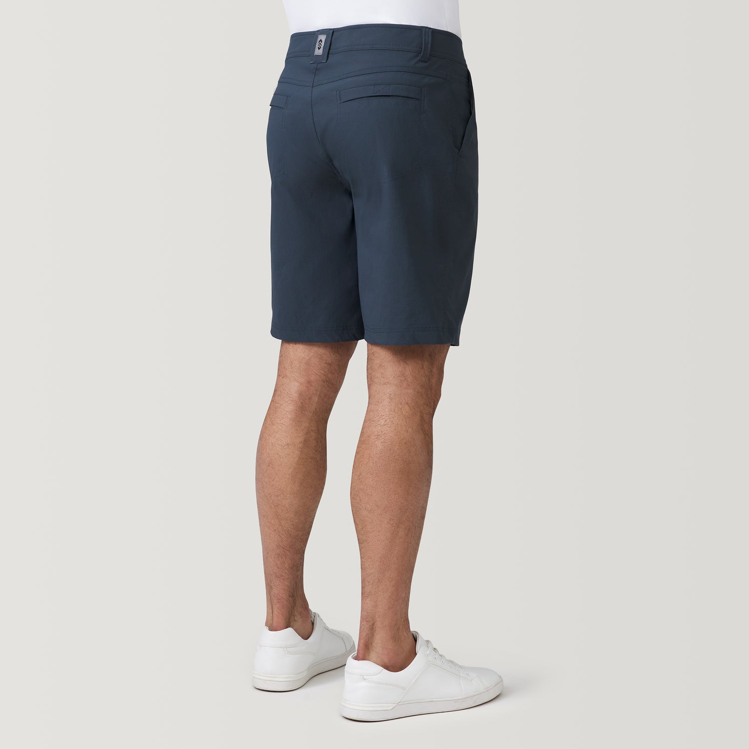 Rear view of a man wearing navy blue water repellent Men’s Nylon Stretch Casual Short and white sneakers.