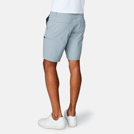 [Josiah is 6'3" wearing a size Medium.] Man wearing Free Country Men's Nylon Stretch Casual Short in Iron, size M, made from lightweight stretch performance fabric featuring a water repellent finish, slanted side pockets, and side leg zippered coin pocket, styled with a white t shirt and white shoes #color_iron