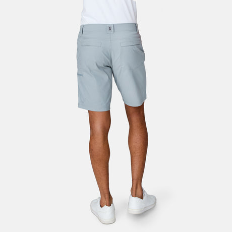 [Josiah is 6'3" wearing a size Medium.] Man wearing Free Country Men's Nylon Stretch Casual Short in Iron, size M, made from lightweight stretch performance fabric featuring a water repellent finish, slanted side pockets, and side leg zippered coin pocket, styled with a white t shirt and white shoes #color_iron