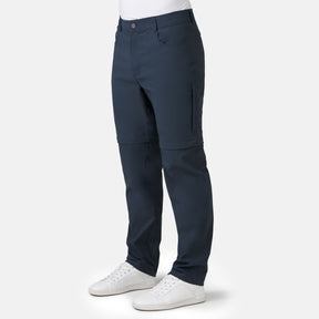 [Model is wearing a size Medium.] Man wearing Men's Nylon Stretch Convertible Pant in Steel, size M, made from lightweight stretch performance fabric featuring a water repellent finish, an elastic waistband, above knee removable pants legs, and two side sipper pockets, styled with a white t shirt and white shoes #color_steel