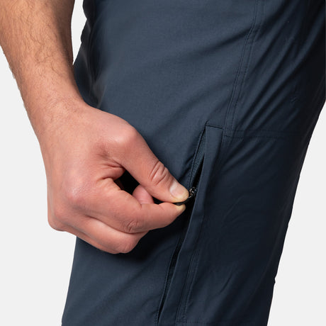 [Model is wearing a size Medium.] Man wearing Men's Nylon Stretch Convertible Pant in Steel, size M, made from lightweight stretch performance fabric featuring a water repellent finish, an elastic waistband, above knee removable pants legs, and two side sipper pockets, styled with a grey t shirt and white shoes #color_steel