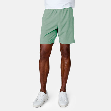 [Anderson is 6'2" wearing a size Medium.]  Man wearing the Free Country Men's Boardwalk Woven Pull-On Trek Short in Basil, size M, made from lightweight breathable polyester fabric and featuring an elastic waistband and slanted pockets, styled with a white t shirt #color_ basil