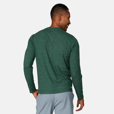 [Anderson is 6'2" wearing a size Medium.] Man wearing Free Country Men's Henley Long Sleeve Shirt in Cilantro, size M, made from lightweight soft polyester fabric featuring a classic fit with anti odor and upf technology, styled with grey shorts #color_cilantro