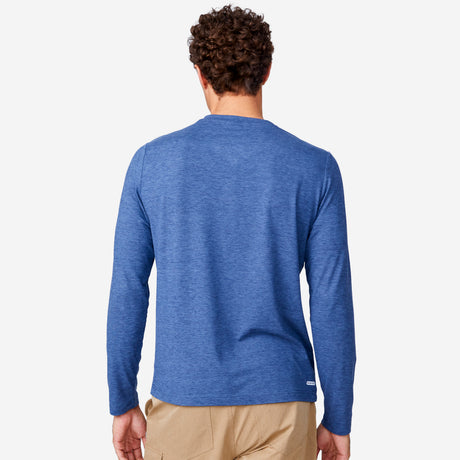 [Miguel is 6'2" wearing a size Medium.] Man wearing Free Country Men's Henley Long Sleeve Shirt in Steel Blue, size M, made from lightweight soft polyester fabric featuring a classic fit with anti odor and upf technology, styled with brown shorts #color_steel-blue